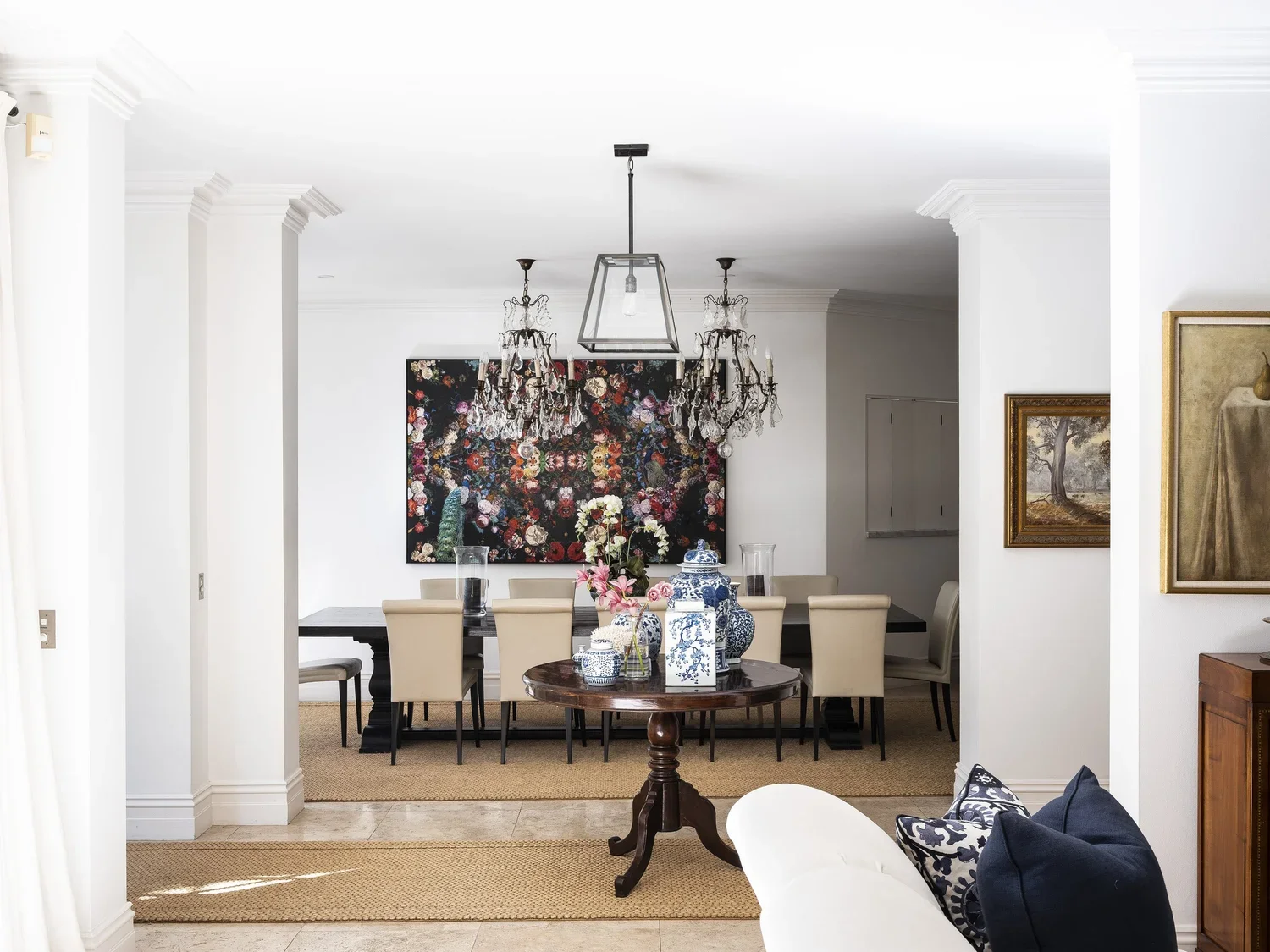 Dining room with chandelier, floral artwork, dining table, and decorative vases.