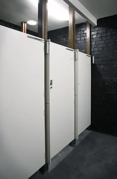 Public restroom with white stall doors and black brick wall.
