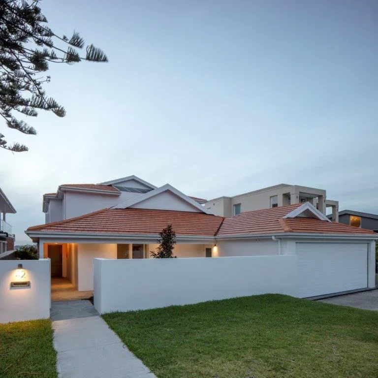 Modern house with white walls, red tiled roof, front lawn, and pathway.