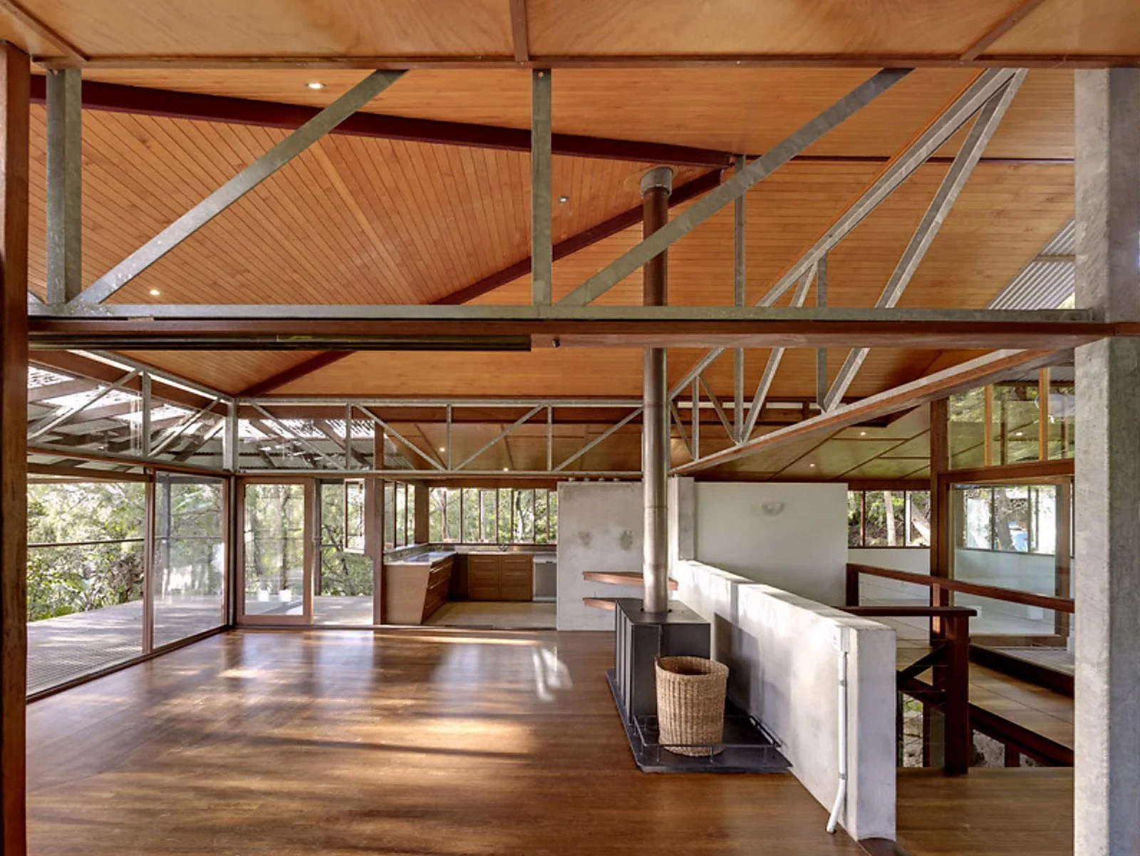Open-plan interior of Tree Top House by Peter Stutchbury, featuring exposed steel trusses and timber finishes.