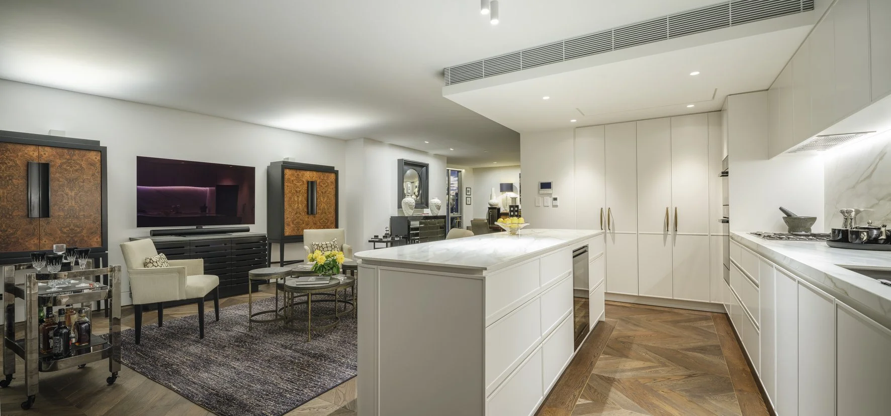 Potts Point Unit 2024 — high-end apartment renovation in Sydney featuring bespoke joinery, herringbone timber flooring with brass inlay, integrated lighting and a cohesive open-plan kitchen, living and dining space.