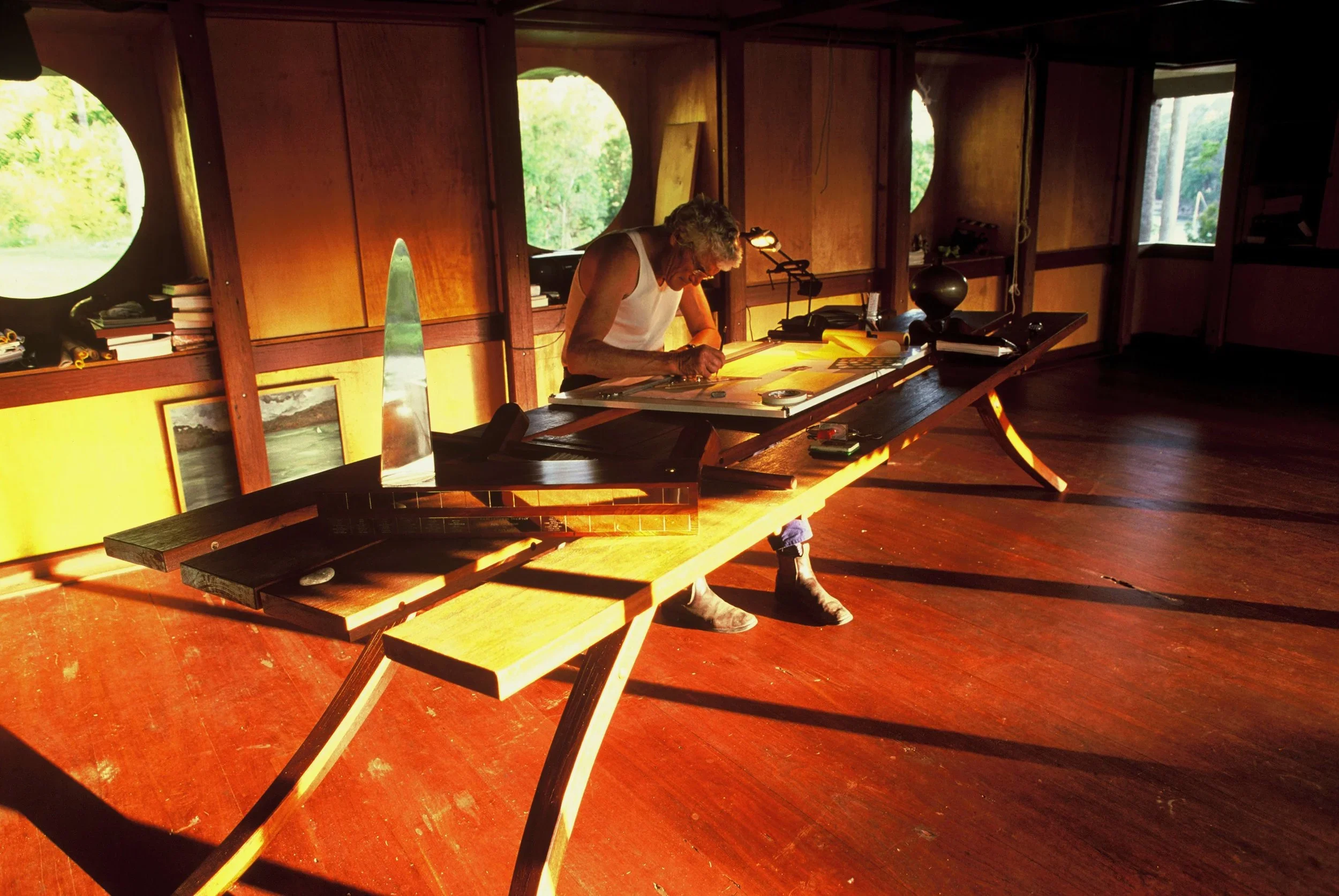 Timber interior of Lovett Bay House, with circular windows, built-in joinery and golden afternoon light across the living space.