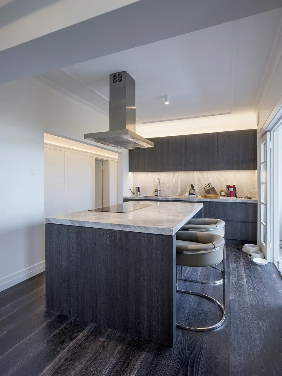 Modern kitchen with dark wood cabinets, a marble island, and stainless steel range hood.