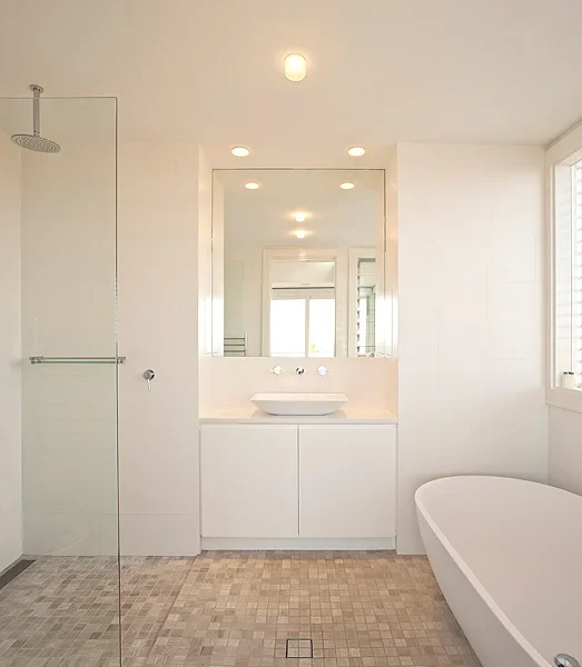 Modern bathroom with a walk-in shower, white vanity with vessel sink, large mirror, and a white bathtub, illuminated by recessed lighting.