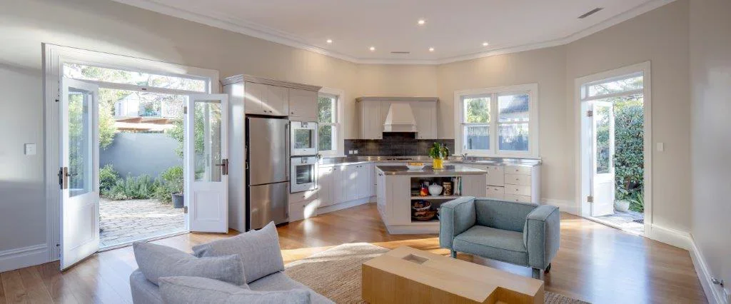 Open-plan living room and kitchen with French doors leading to a garden, modern kitchen appliances, and a cozy seating area.