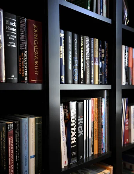 Black bookshelf filled with various hardcover and paperback books.