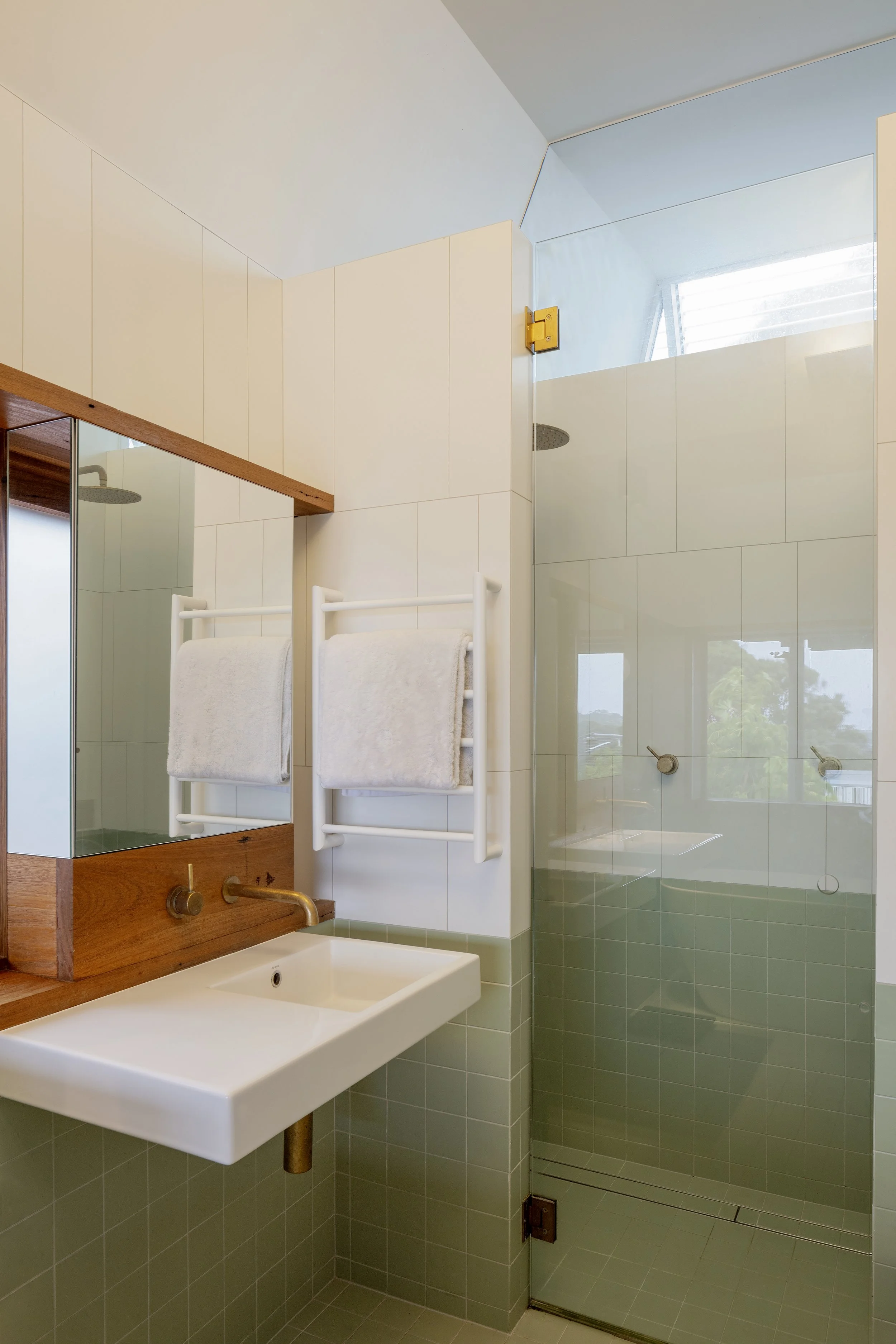 Bathroom with twin basins, a glass shower and timber-framed windows.