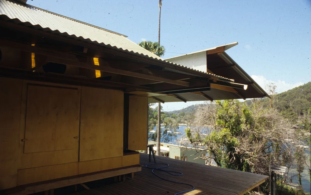 Lovett Bay House exterior with timber cladding, corrugated roof and wide deck facing the water-access site in Pittwater.