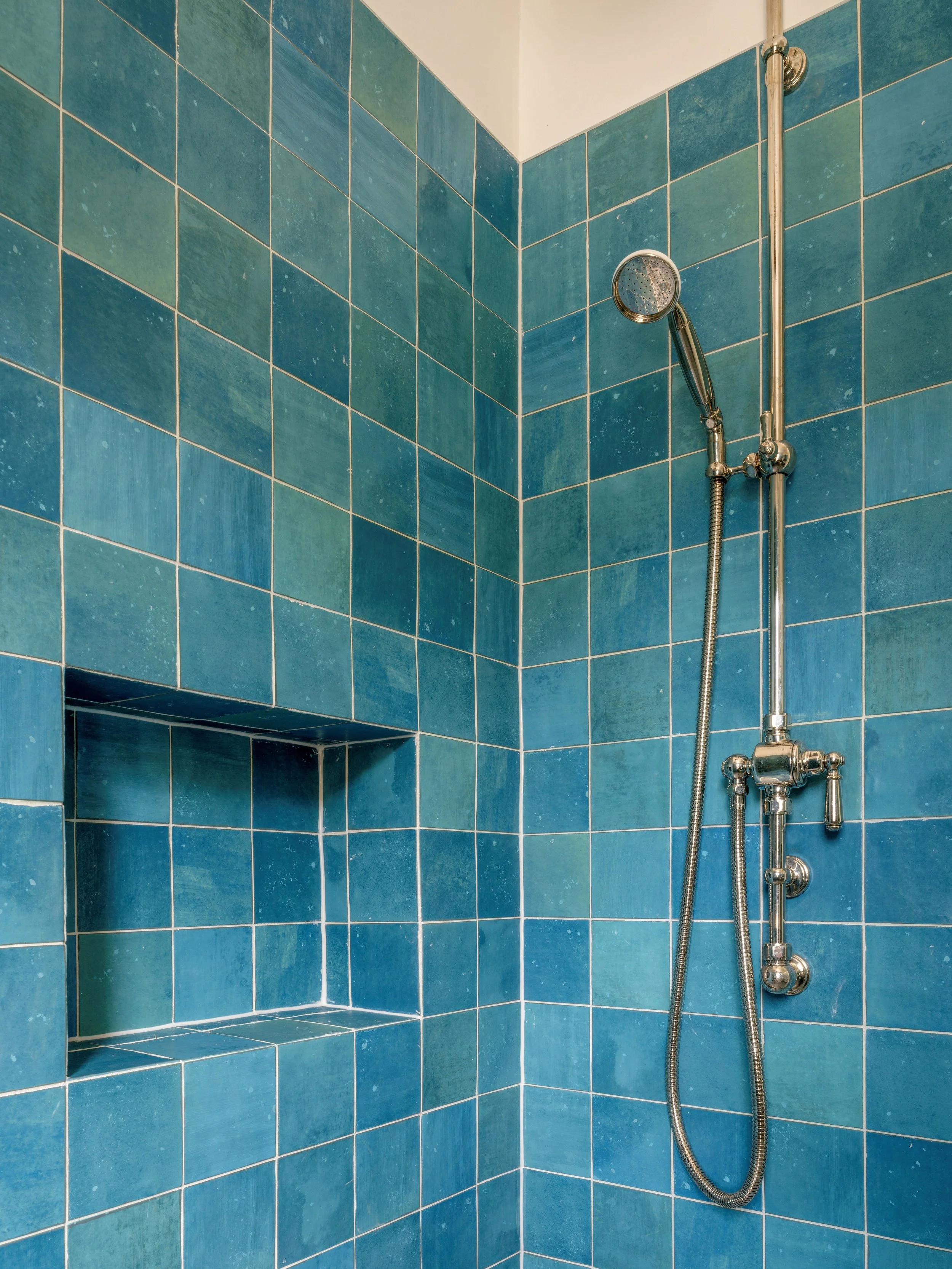 Bathroom shower at Vaucluse House textured blue tiles, a tiled storage niche and traditional chrome fittings.