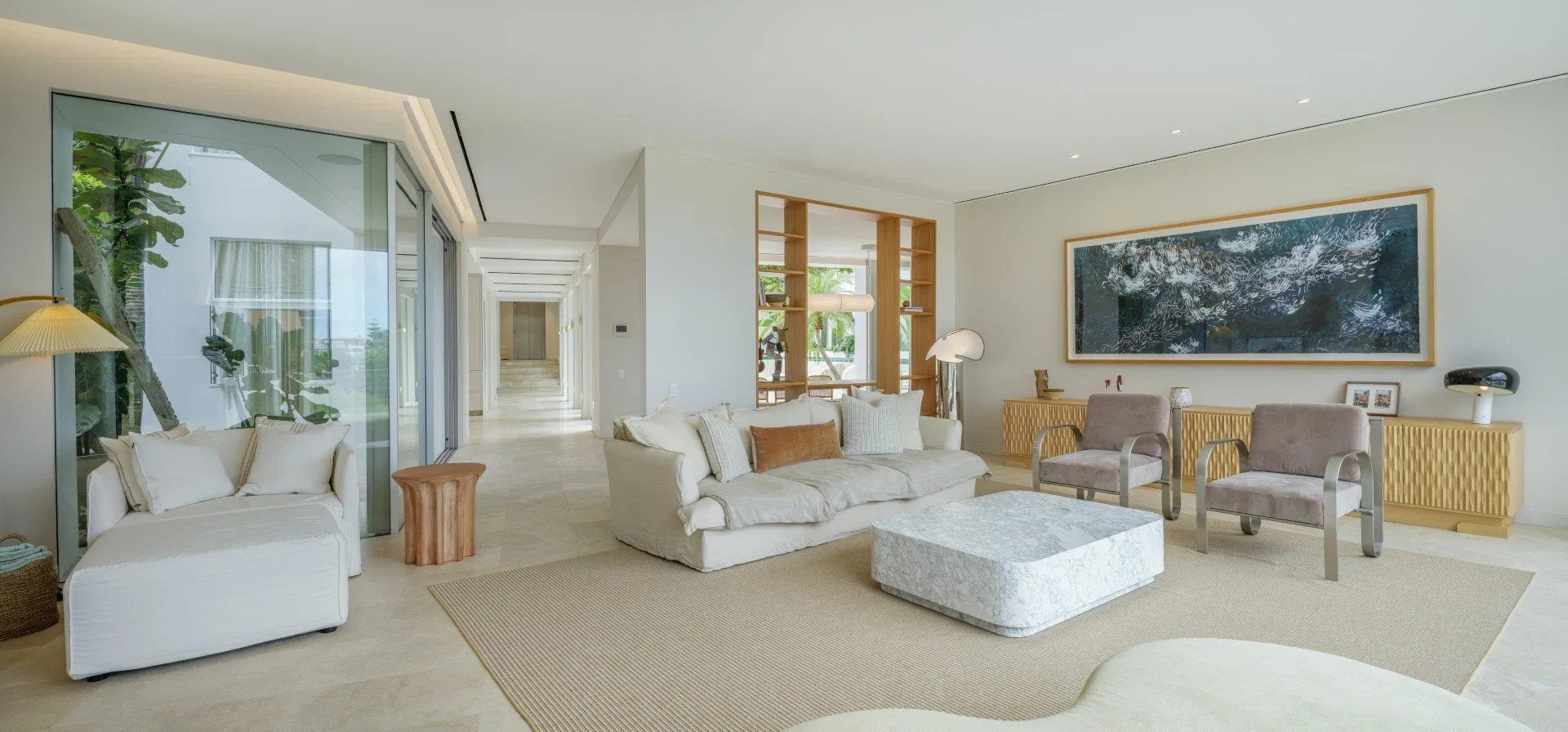 Living room with modern furniture, large window, artwork, and neutral colors