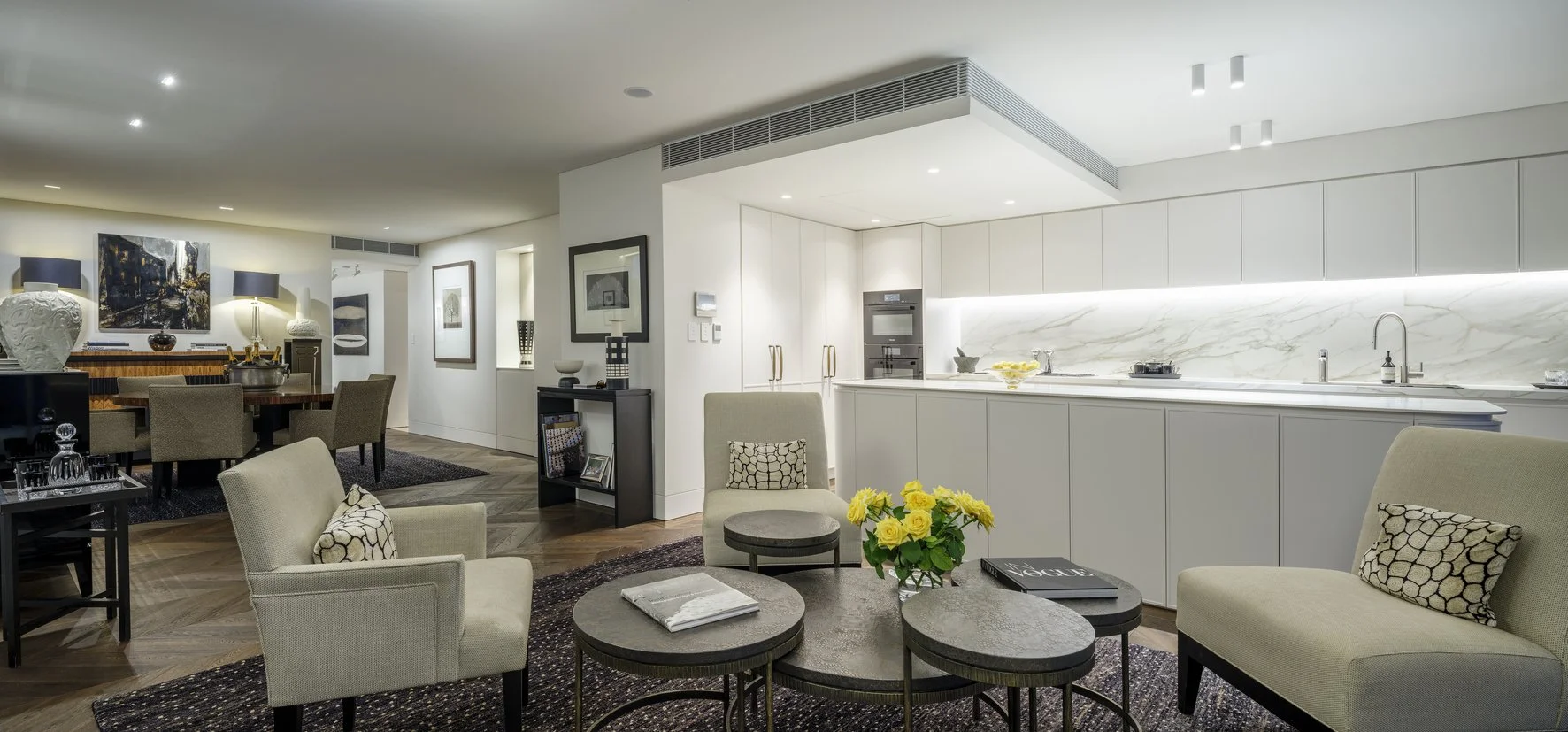 Potts Point Unit 2024 — high-end apartment renovation in Sydney featuring bespoke joinery, herringbone timber flooring with brass inlay, integrated lighting and a cohesive open-plan kitchen, living and dining space.