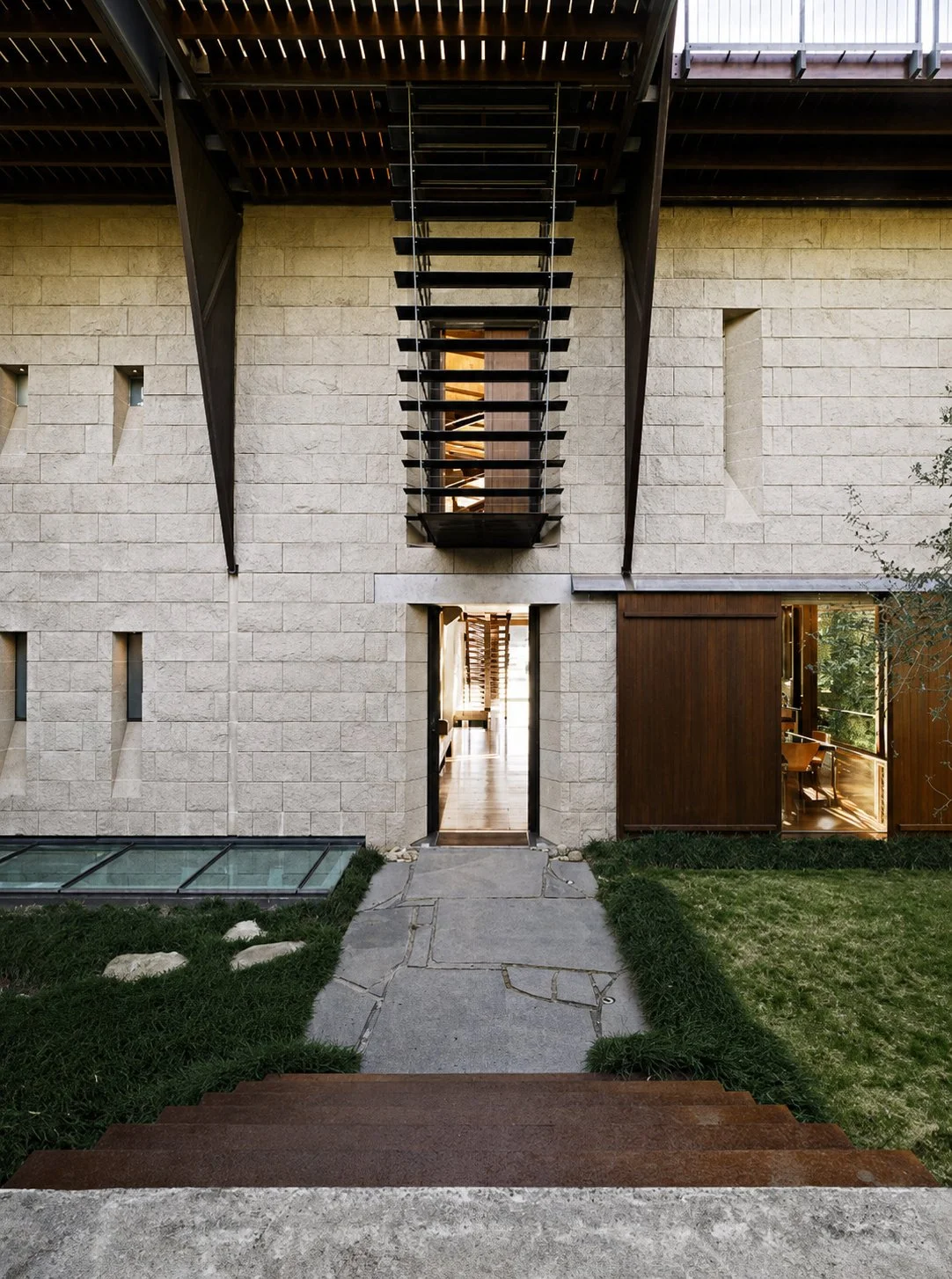 Designed by Peter Stutchbury.  View from Bay House into the central garden, with timber screens casting patterned sunlight across the blockwork walls.