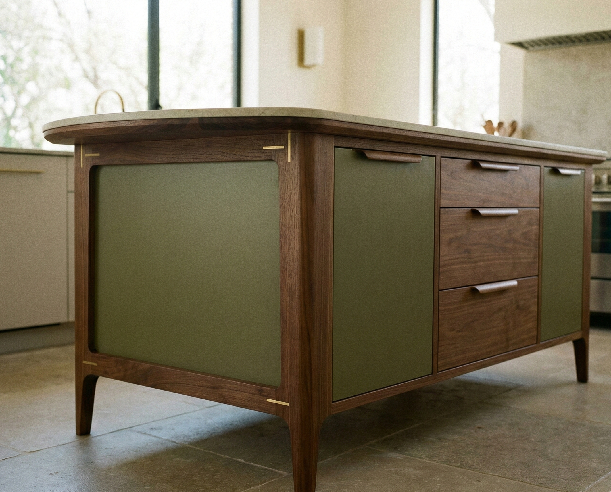 Mid-century modern kitchen island with a wooden frame, green front panels, and three drawers in the center, situated in a bright kitchen with a large window.