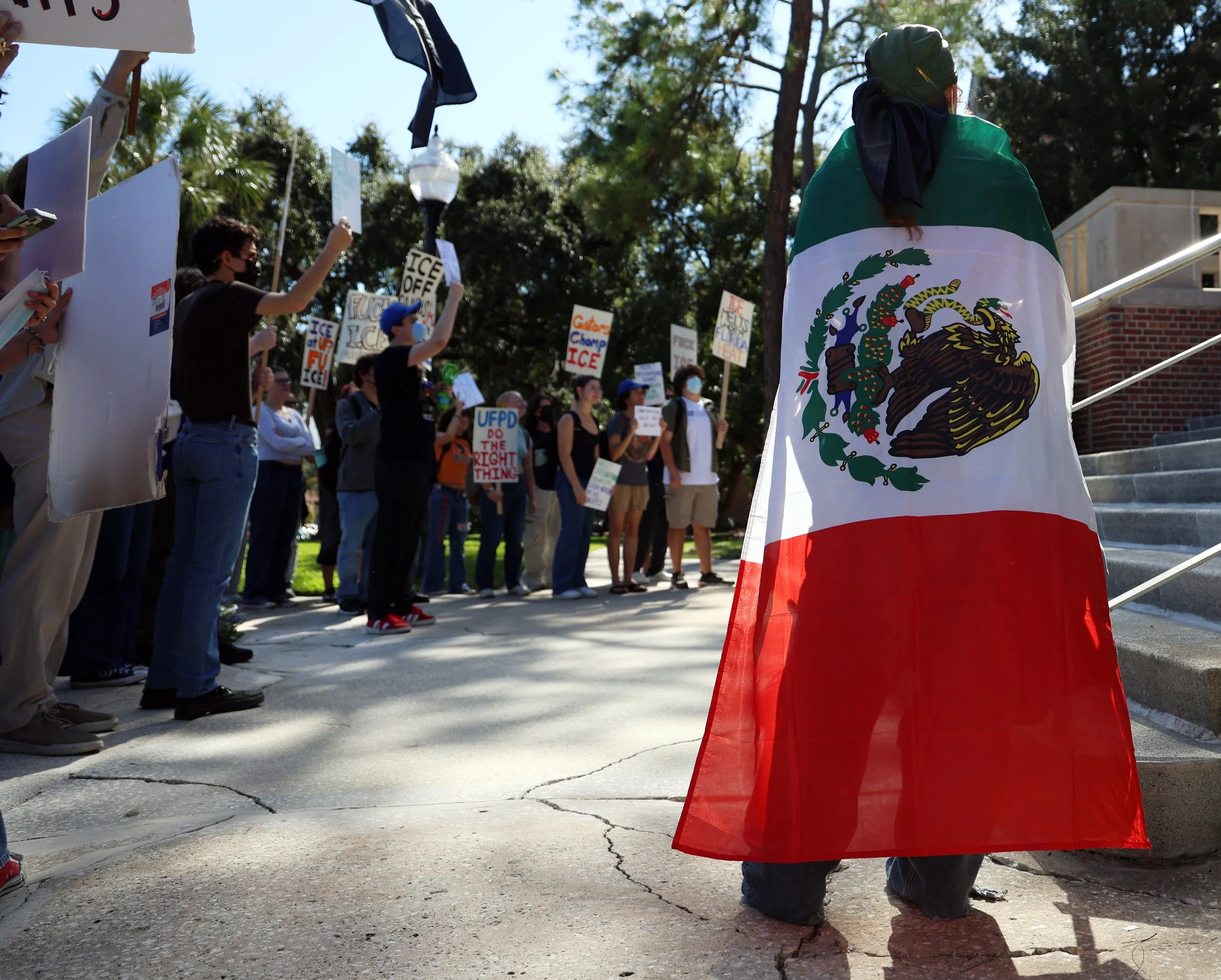 A protestor wears a Mexican flag as a cape outside  Tigert Hall, the University Administration building, on Wednesday, Nov. 5, 2025, in protest of the University of Florida’s decision to partner with ICE.