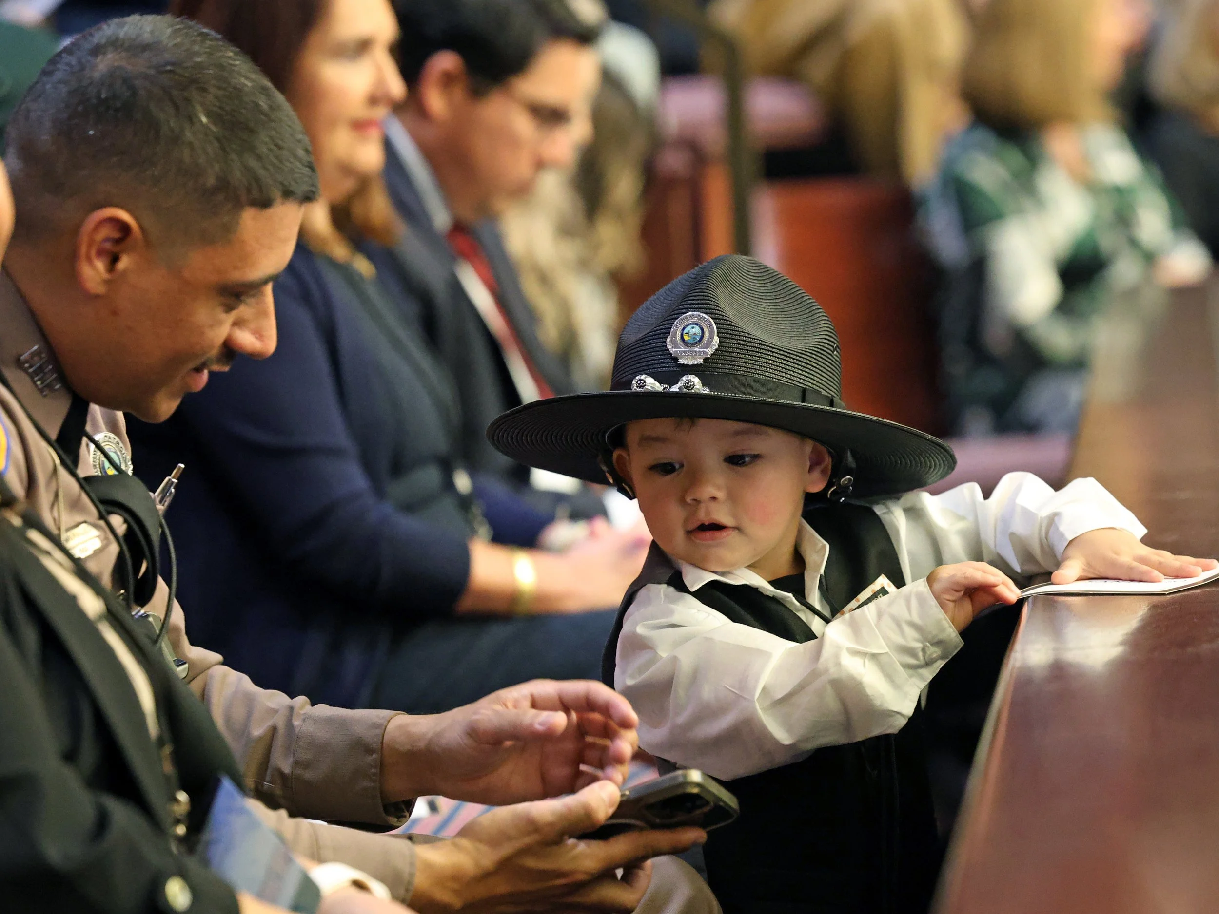 Florida Trooper Orlando Morales' son wears his hat before the State of the State Address in Tallahassee, Fla., on Tuesday, March 4, 2025. Gov. Ron DeSantis highlighted how he rescued an abandoned dog during Hurricane Milton during his speech.