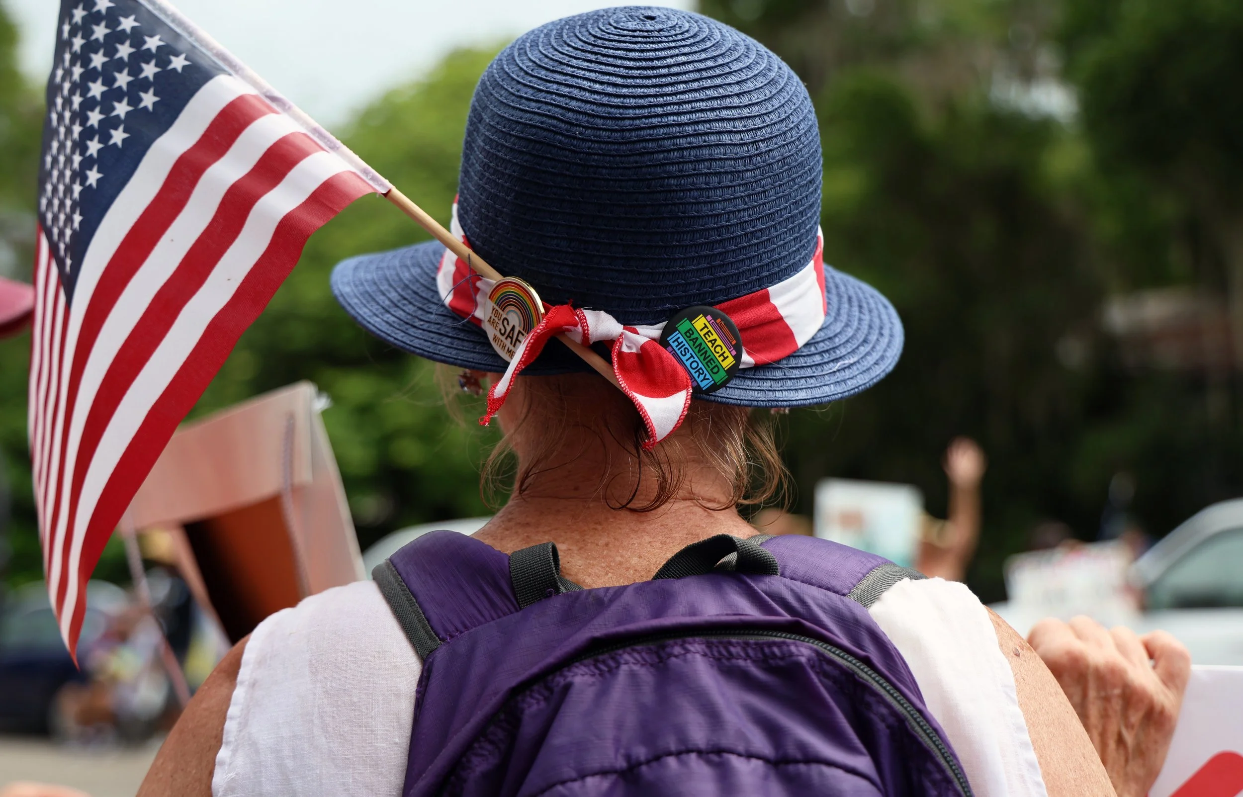 A protestor dawns a hat on the side  of Southwest Sixth Street during the "No Kings Day" protest on Saturday, June 14, 2025.