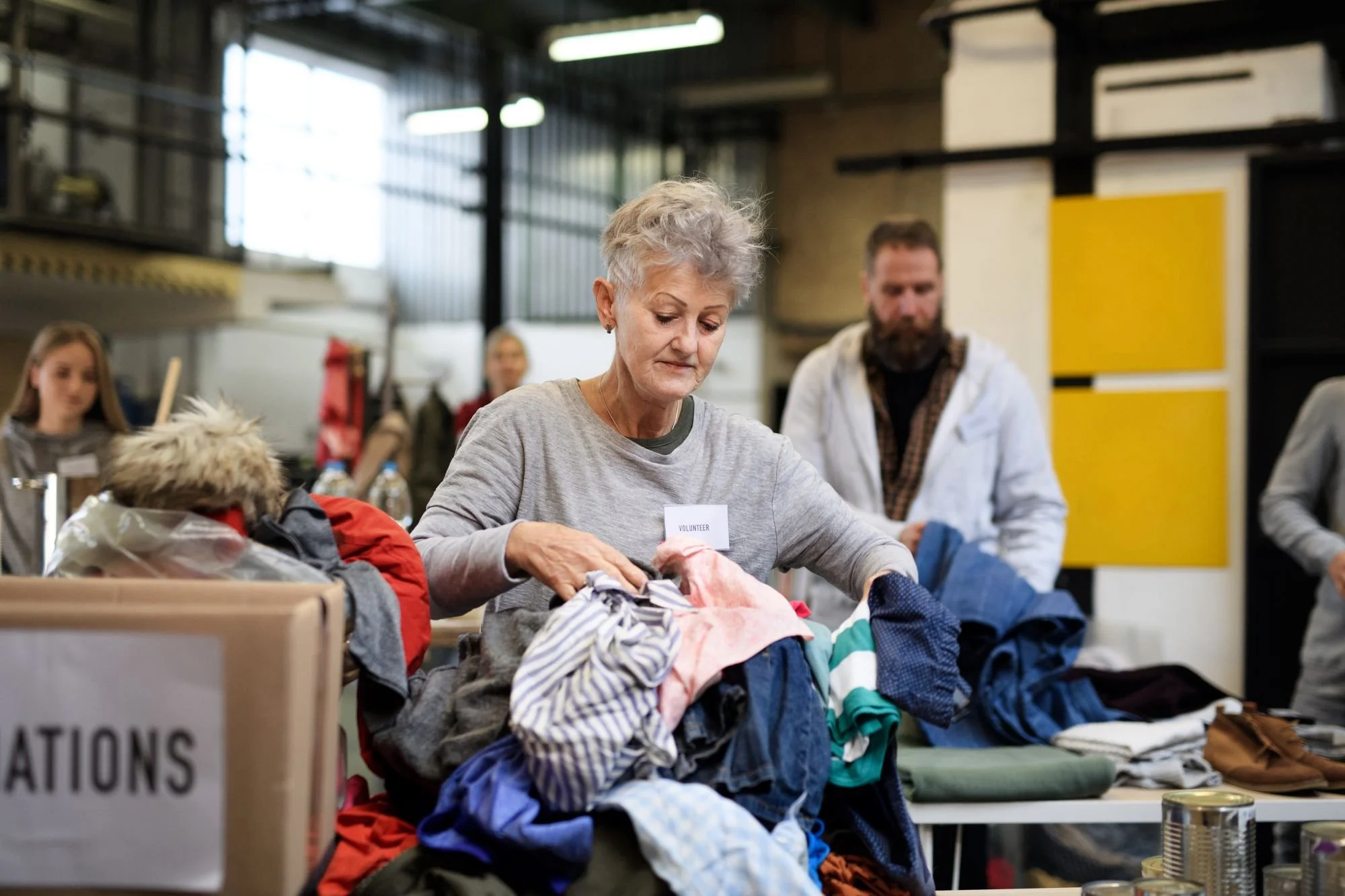Volunteer sorting through piles of clothes at a donation center