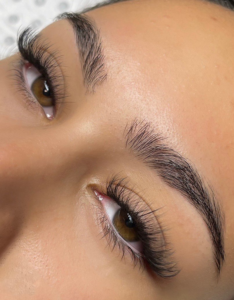 Close-up of a person's face showing well-groomed eyebrows, long eyelashes, and smooth skin.