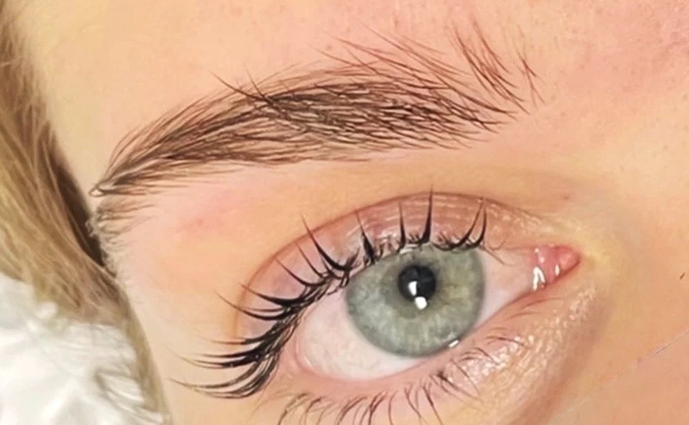 Close-up of a green eye with long curled eyelashes and well-shaped eyebrow.