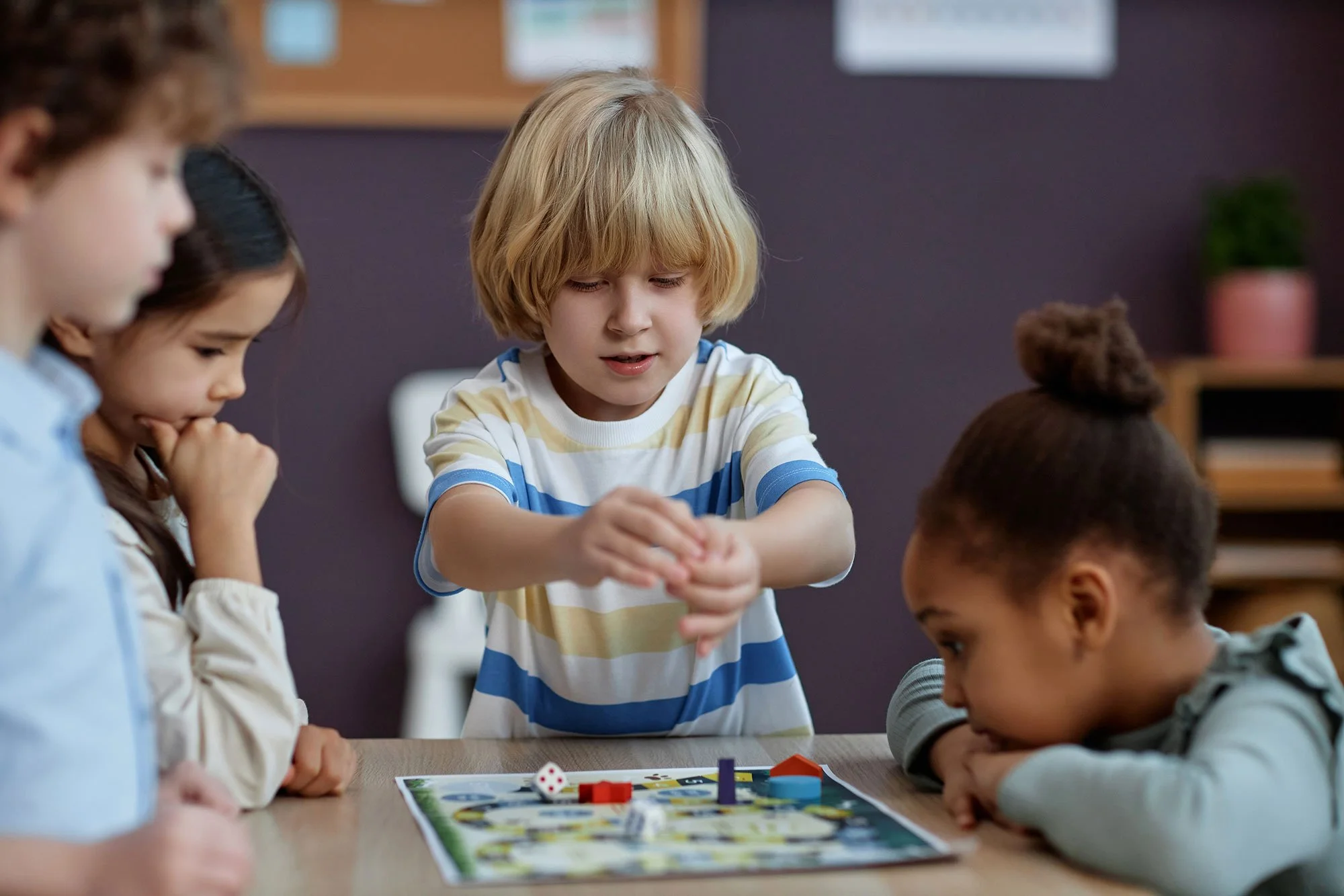 Children playing a board game at a table indoors.