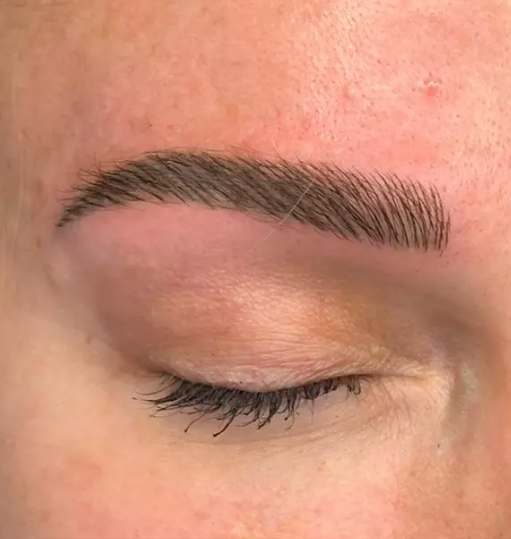 Close-up image of a closed eye with well-groomed eyebrows and long eyelashes.