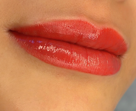 Close-up of lips with shiny red lipstick.
