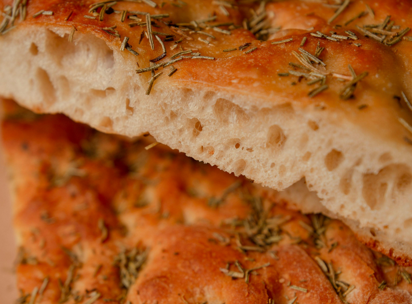 A side-cut slice of the Ultimate Airy Focaccia highlighting its tall, honeycomb-like interior and light, bubbly crumb.