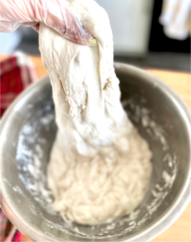 Close-up of dough being mixed in a stainless steel bowl.