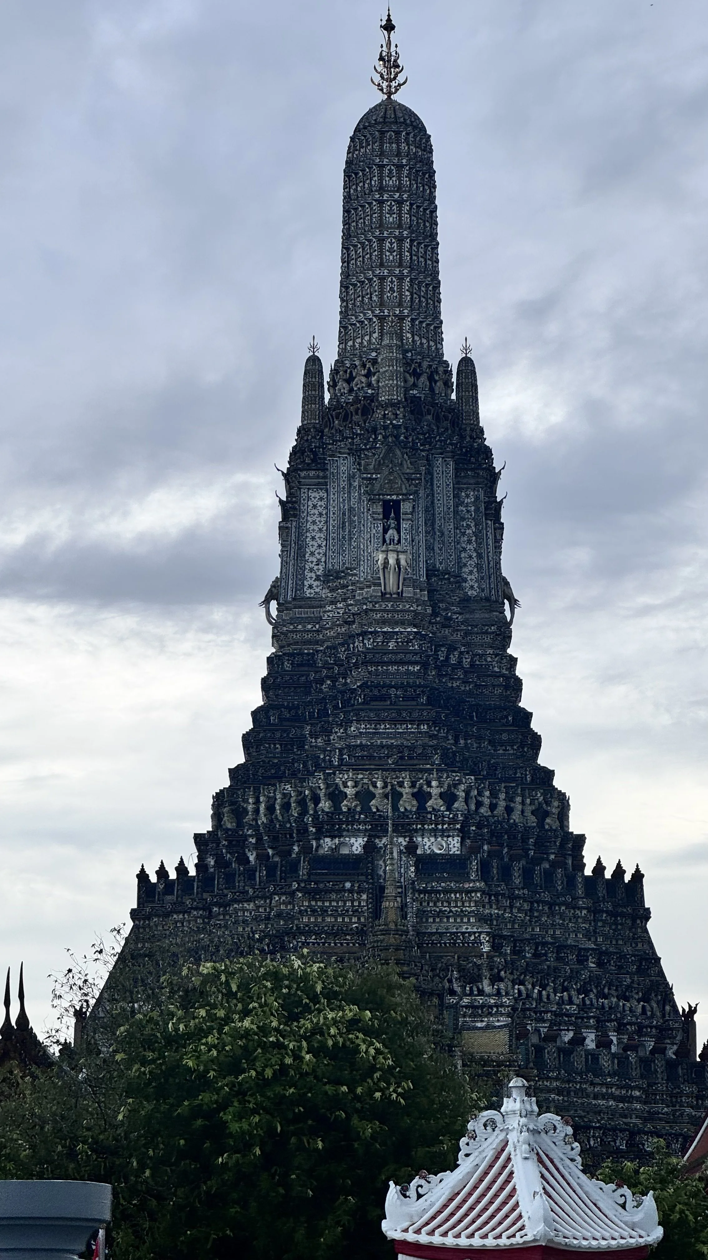 Templo em estilo tradicional dourado e preto, com estrutura elevada e detalhes elaborados, sob céu nublado.