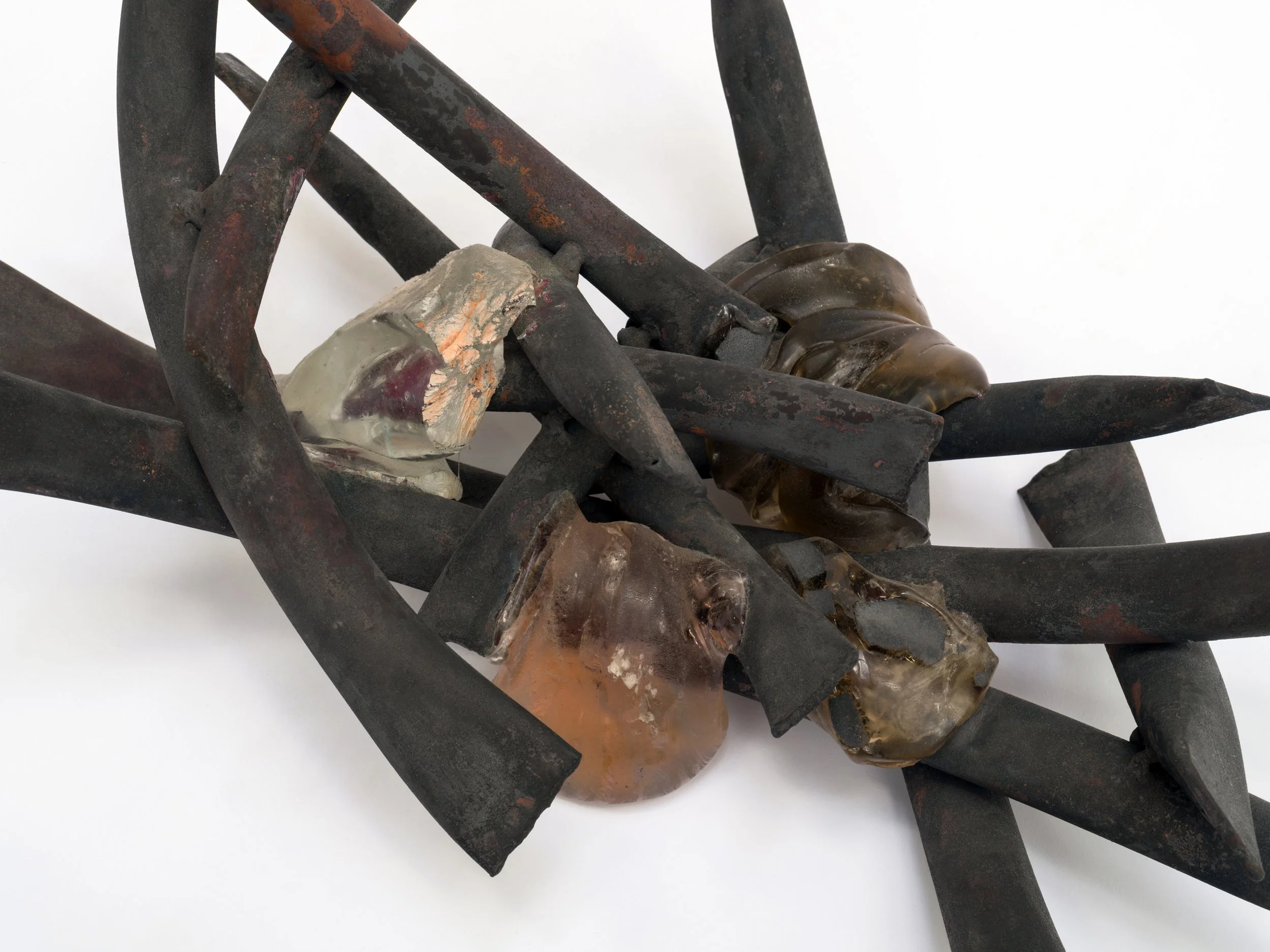 Close-up view of rusted metal objects, possibly tools or parts, with some areas that appear painted or coated, against a white background.
