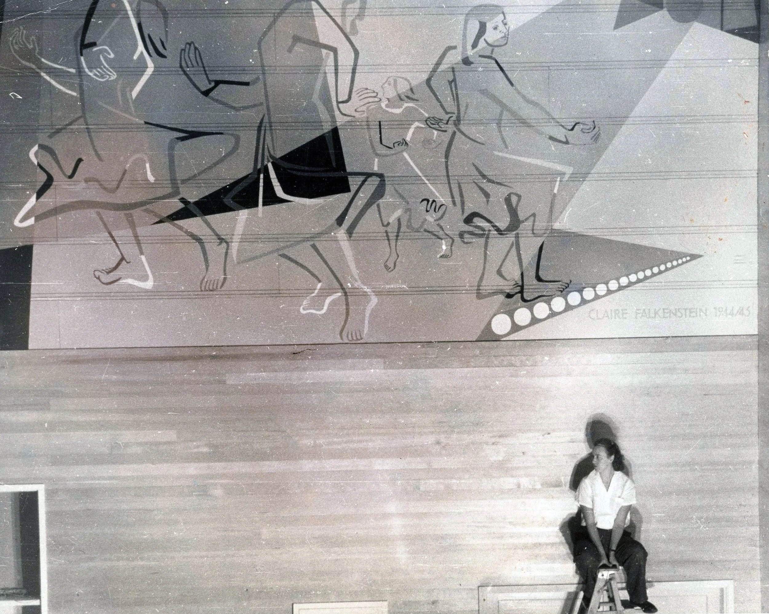 Black-and-white photograph of a mural high on a wall featuring outlines of people rendered in a simplified modernist style. A young Claire Falkenstein is seated on a ladder in the lower right.