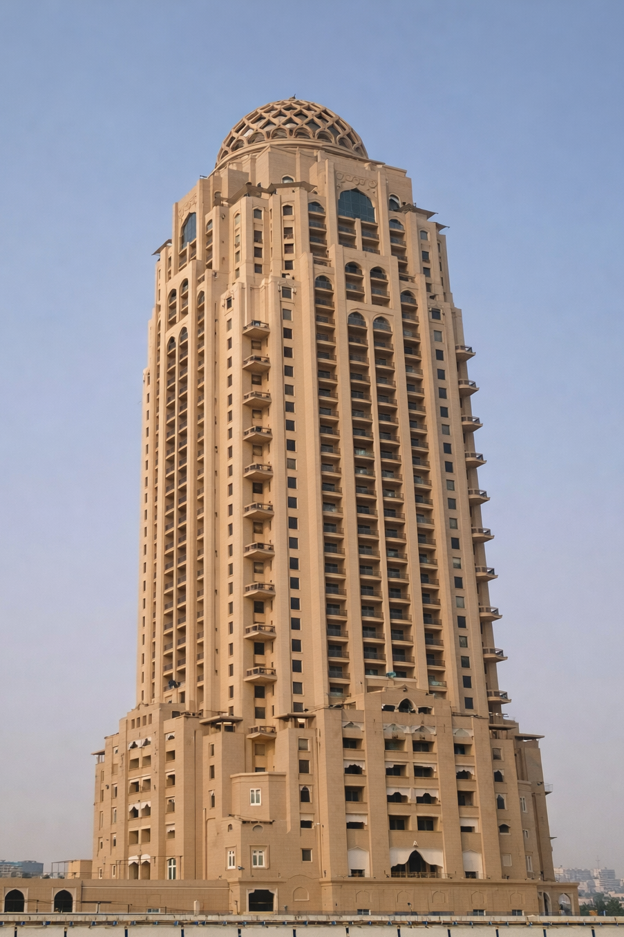 Tall beige skyscraper with a dome-shaped top against a clear sky.