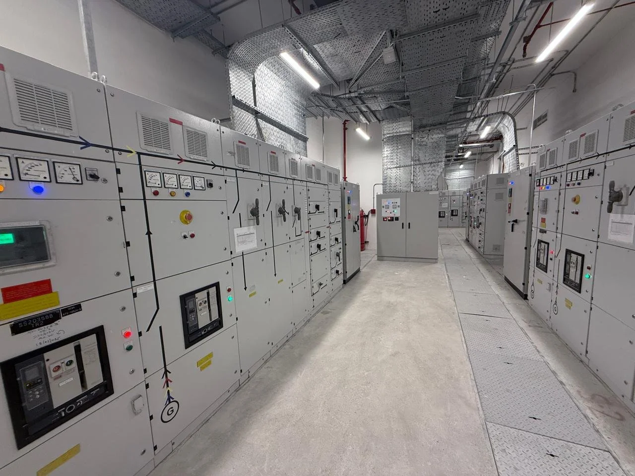 View of an industrial electrical control room with multiple large electrical panels and equipment.