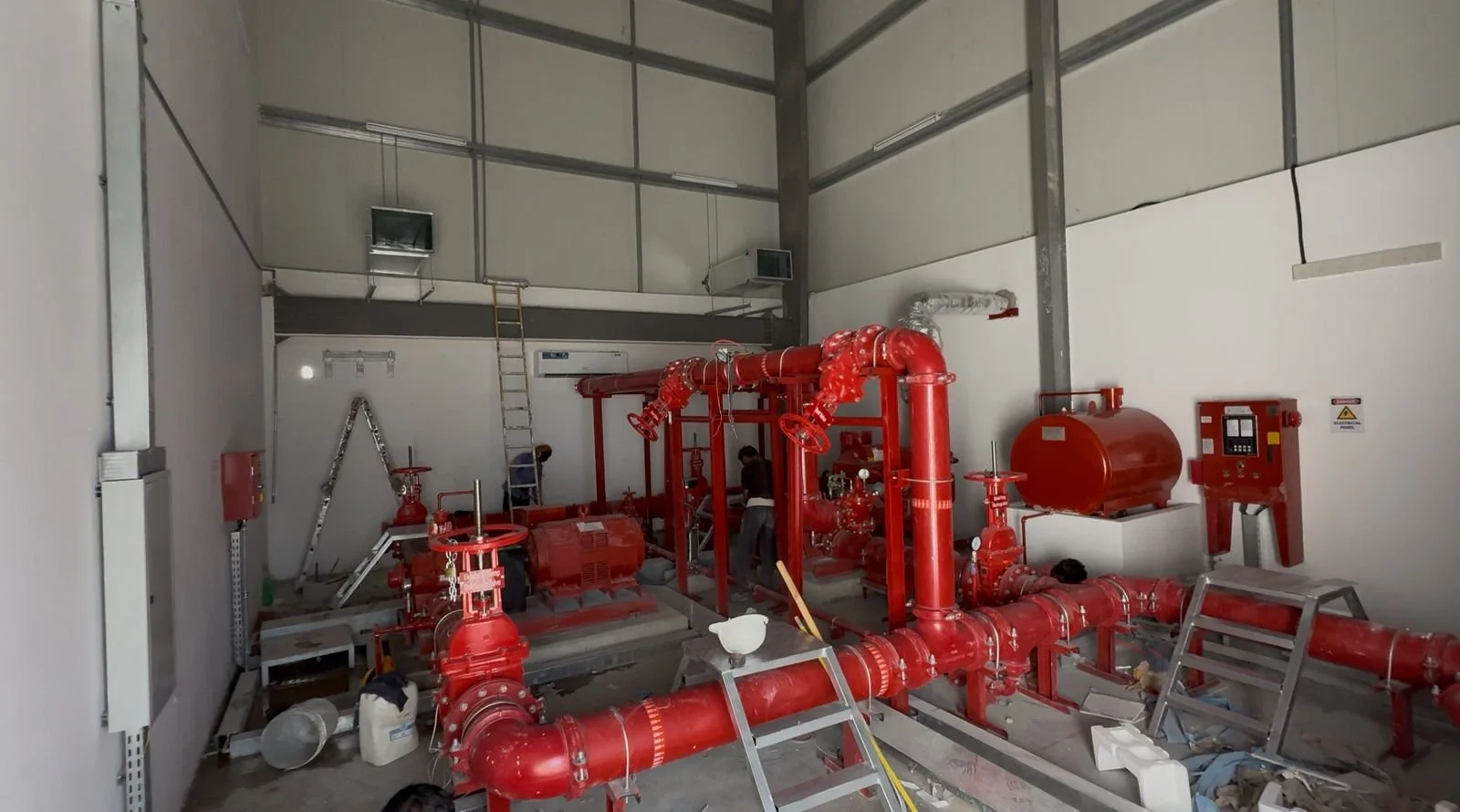 Industrial fire suppression system with red pipes, valves, and tanks in a manufacturing or storage facility.