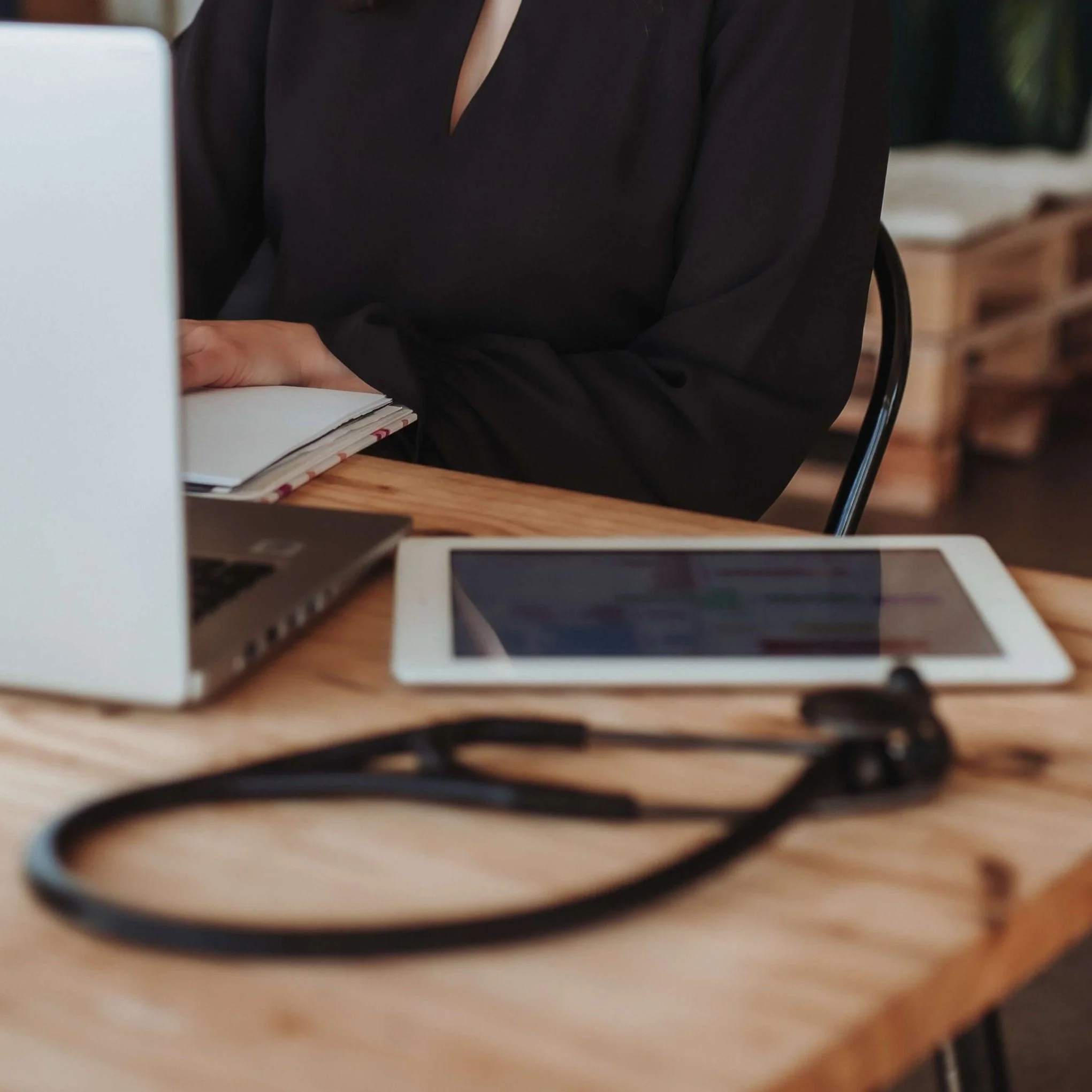 working desk with a laptop, ipad and stethoscope