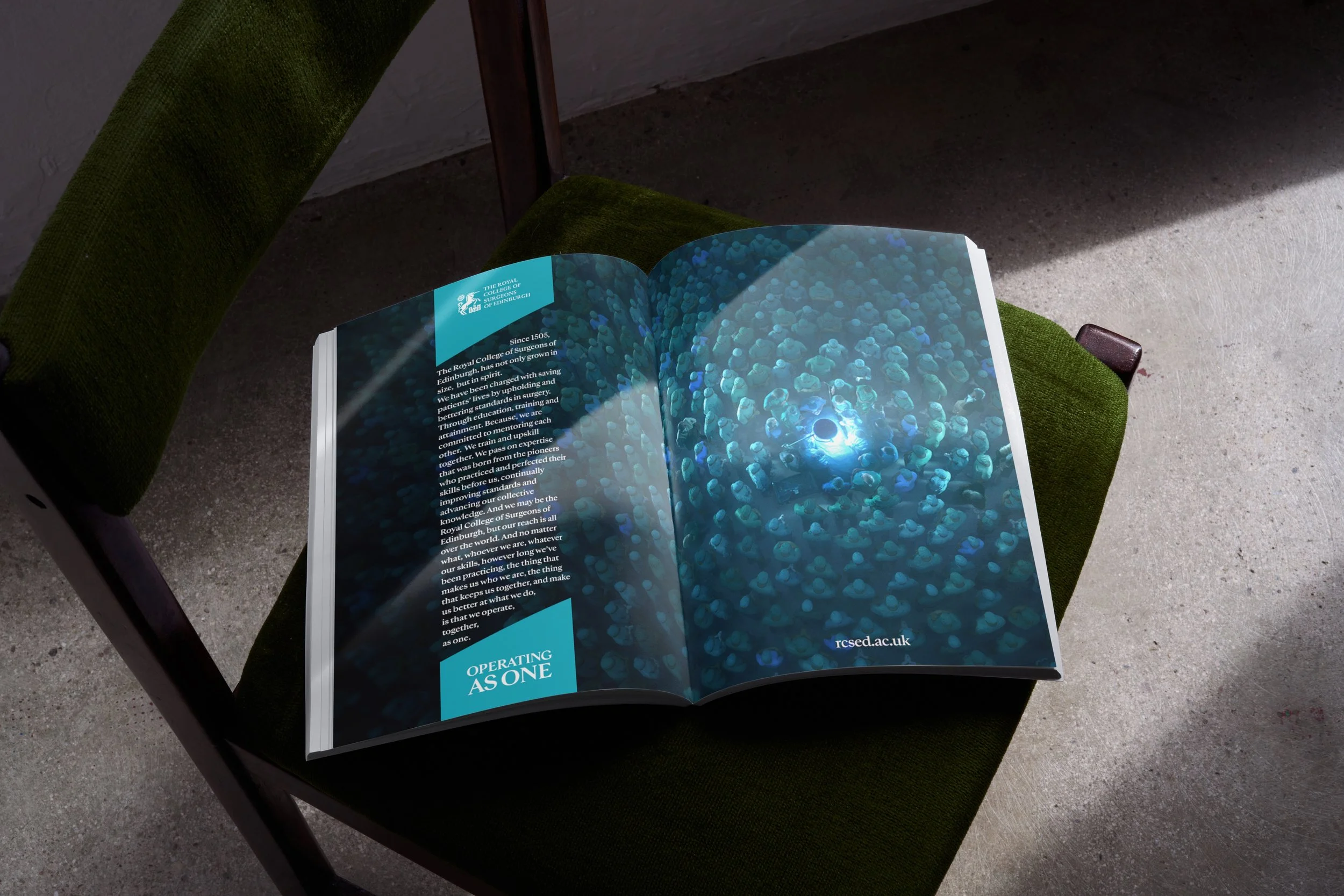 Open booklet on a green upholstered chair, with a blue programmatic design of cells and a light in the center. The booklet features the Royal College of Surgeons of Edinburgh logo and text about their history and mission.