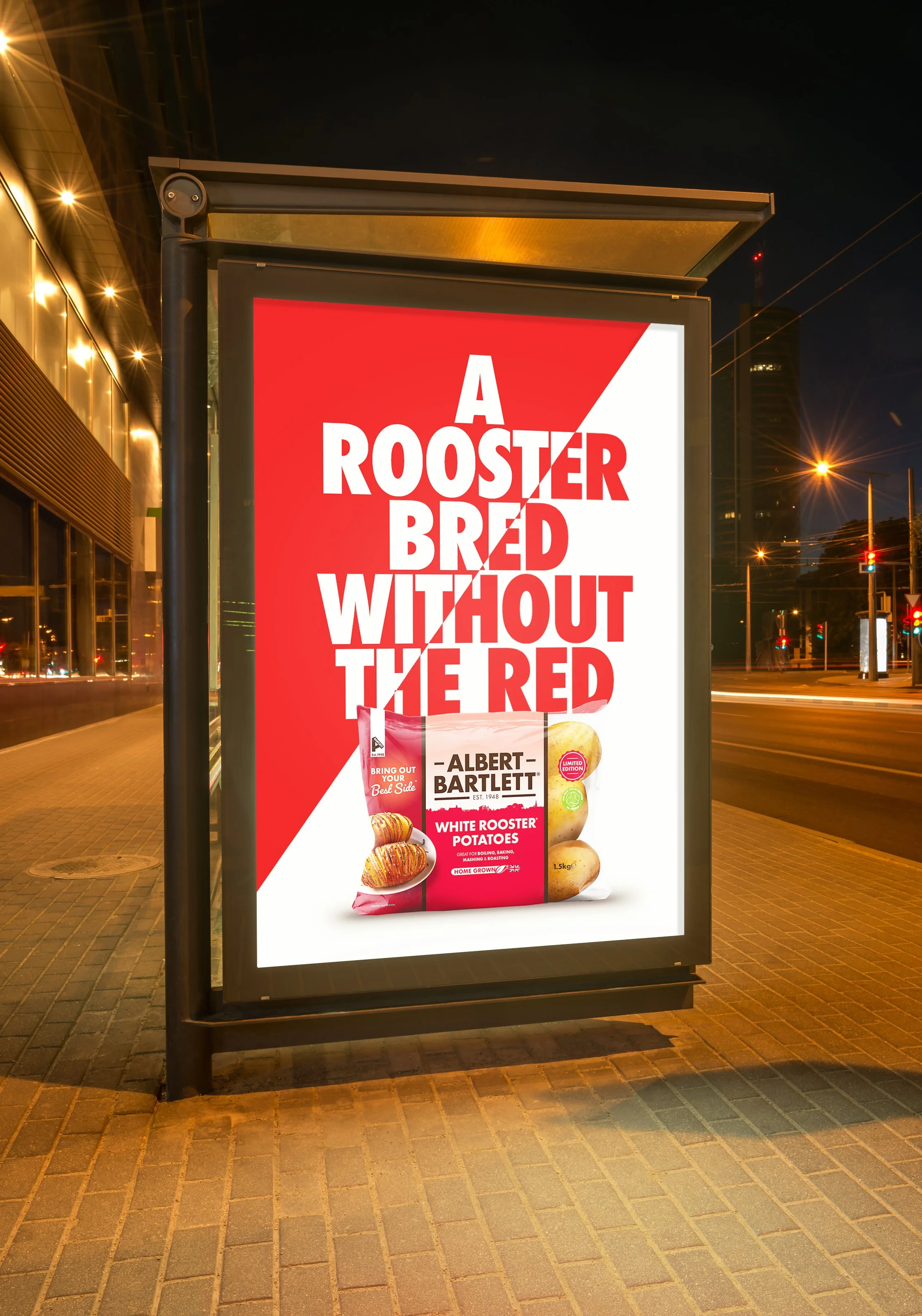 Advertising poster on a city sidewalk featuring red and white text that reads 'A Rooster Bred Without the Red' and an image of a bag of Albert Bartlett white Rooster potatoes.