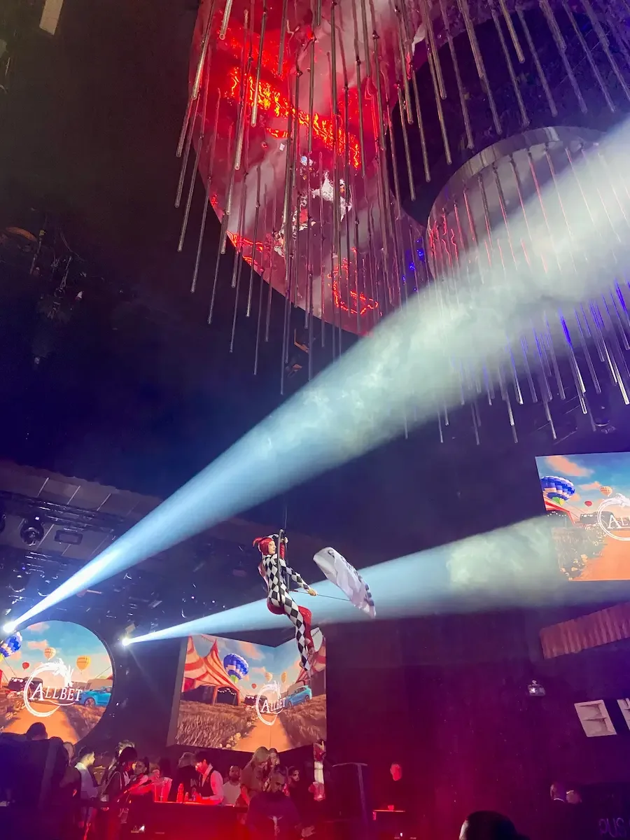 Trapeze artist in checkered costume performing at circus-themed corporate event