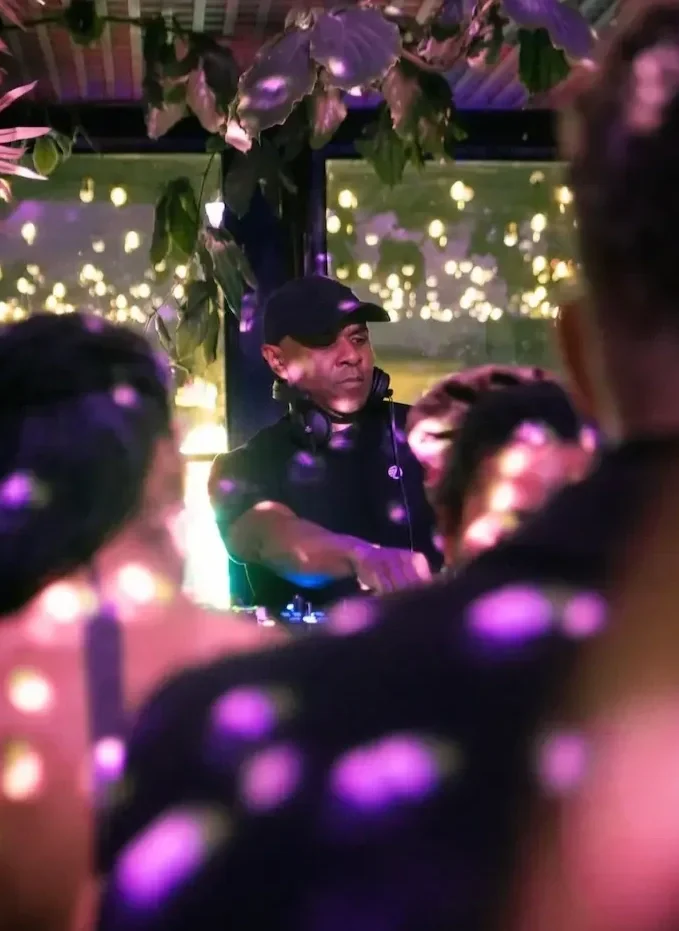 DJ in black performing at lively indoor party with bokeh lighting