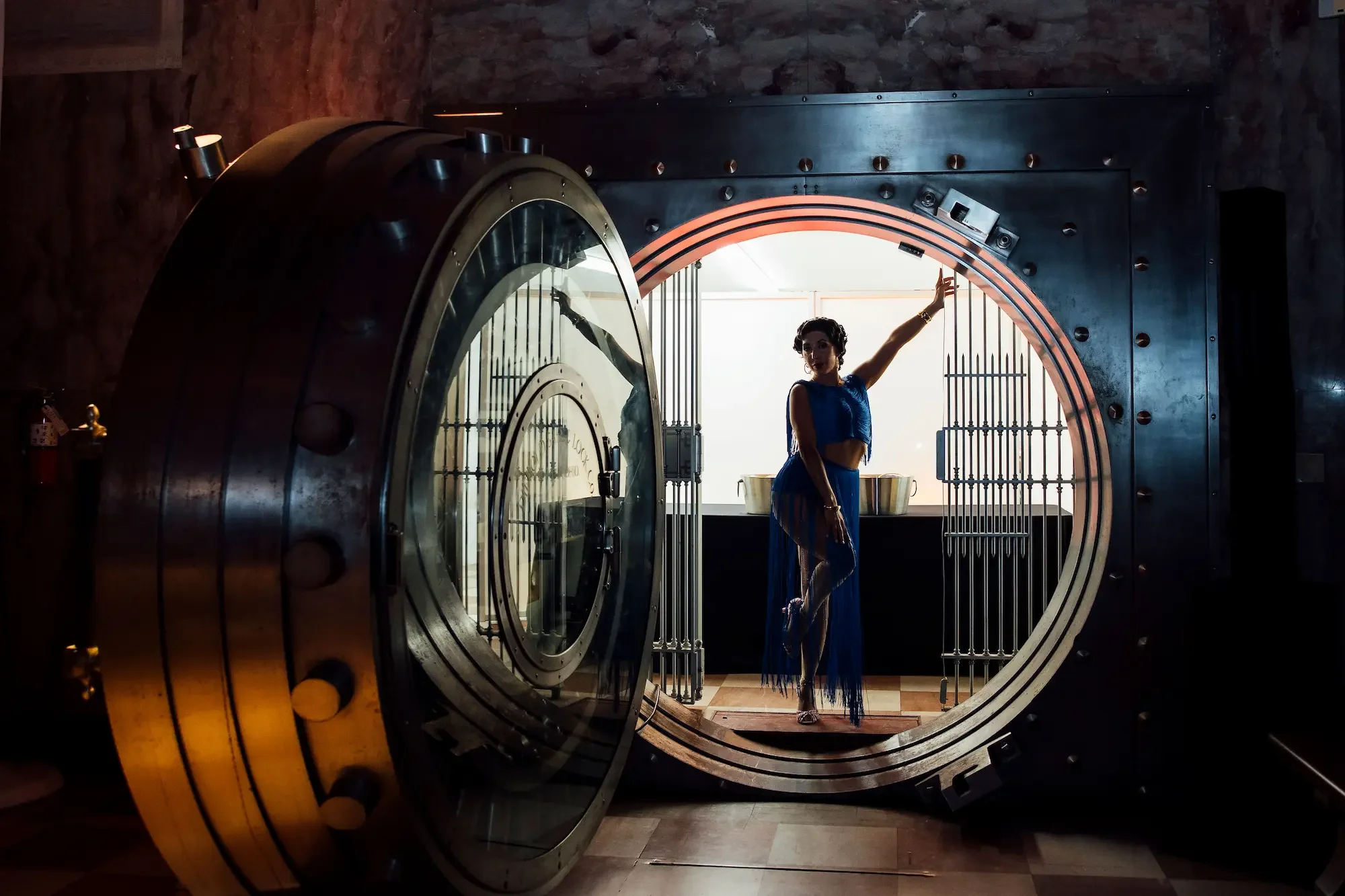 Performer in blue dress posing inside open bank vault