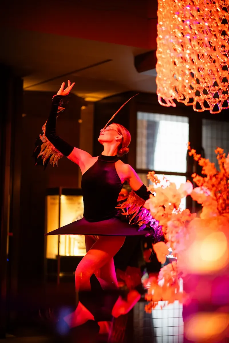 Ballerina in feathered costume performing beneath grand chandelier