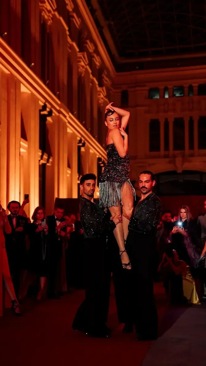 Acrobatic trio performing a lift in an outdoor elegant venue with an audience