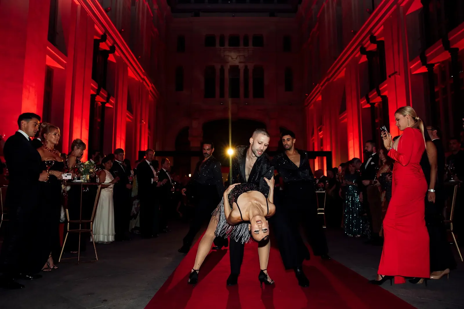 Couple dancing on red carpet at elegant gala with glamorous audience