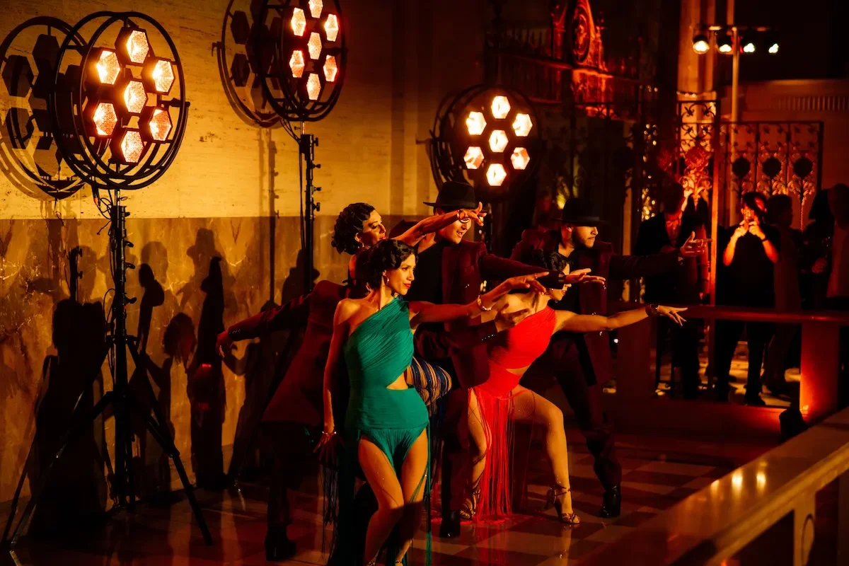 Dancers in colorful costumes performing on warmly lit stage for a gala dinner event.