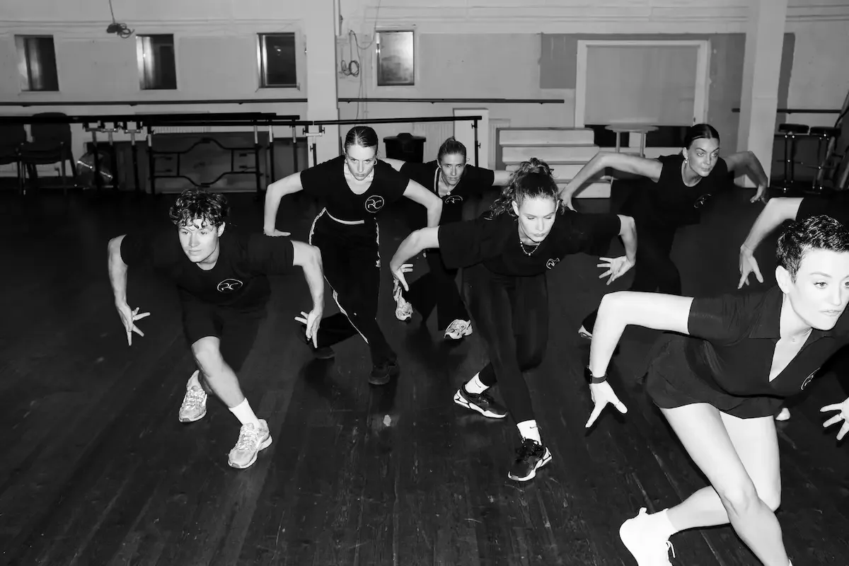 Dancers in black rehearsing choreography in dance studio