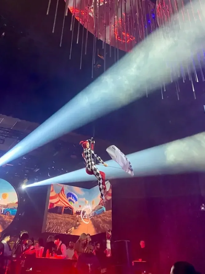 Trapeze artist in checkered costume performing at circus-themed corporate gala