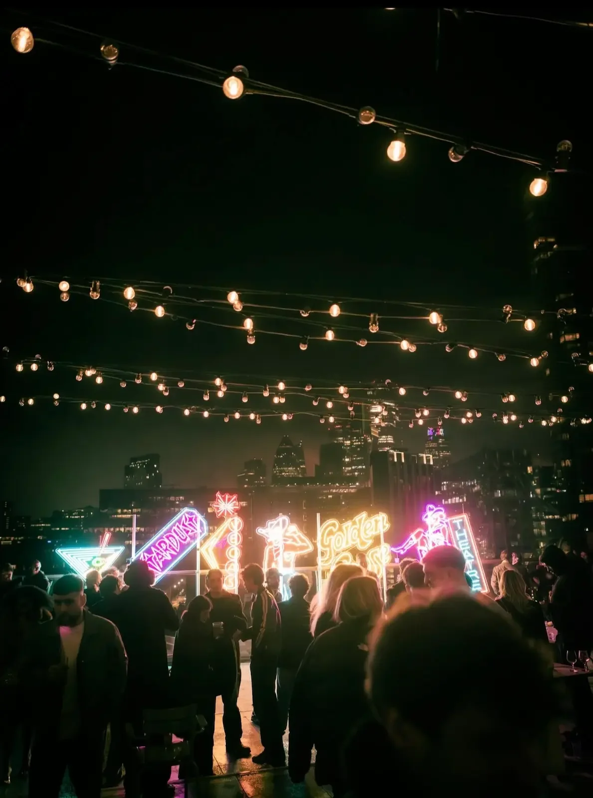 Rooftop party with neon lights and city skyline at night