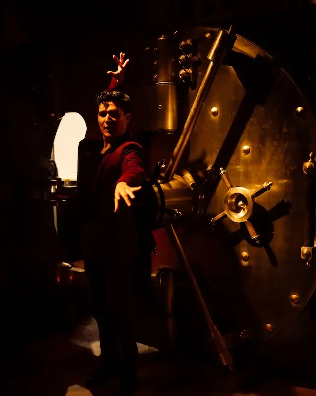 Performer dancing beside an ornate bank vault combination wheel