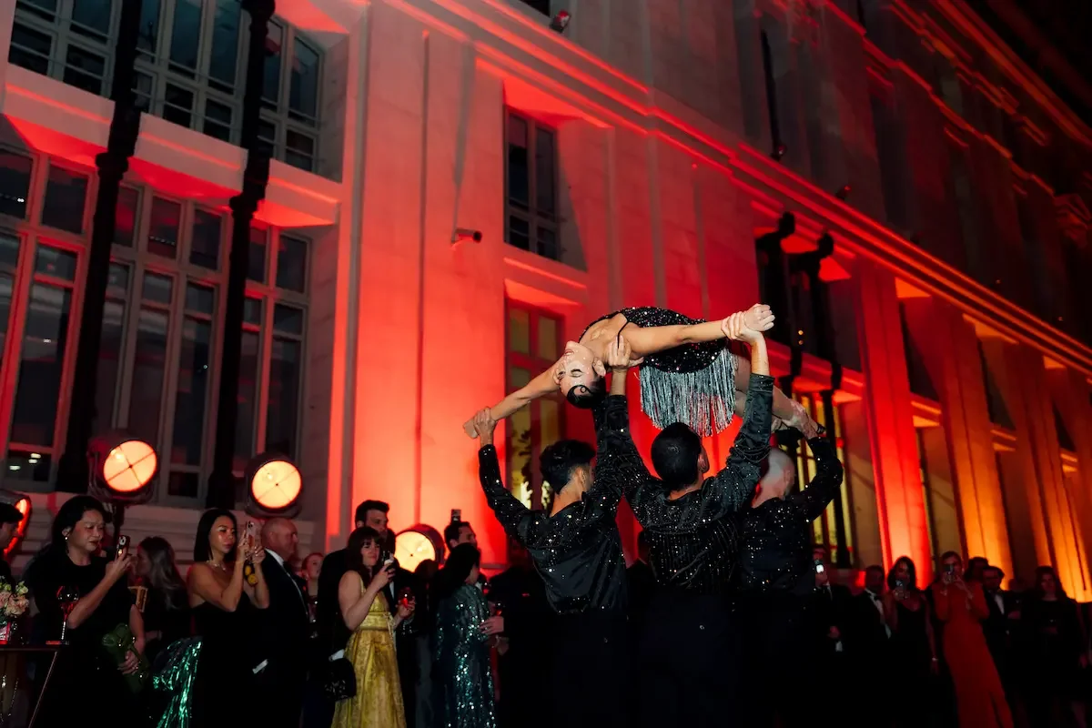 Dancers performing acrobatic lift at red-lit red carpet celebration