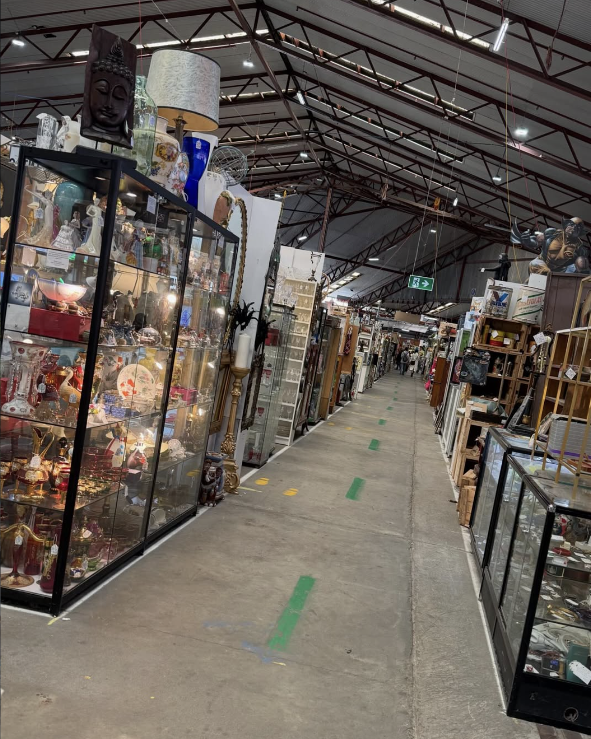 Inside Waverley Antique Bazaar with glass display cases filled with collectibles, decorations, and antiques, and aisles with various furniture and items for sale.